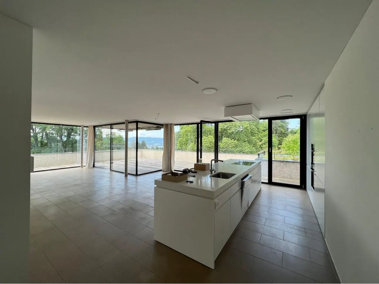 Penthouse in Küsnacht ZH: Wohnraum mit Küche und Blick ins Grüne
